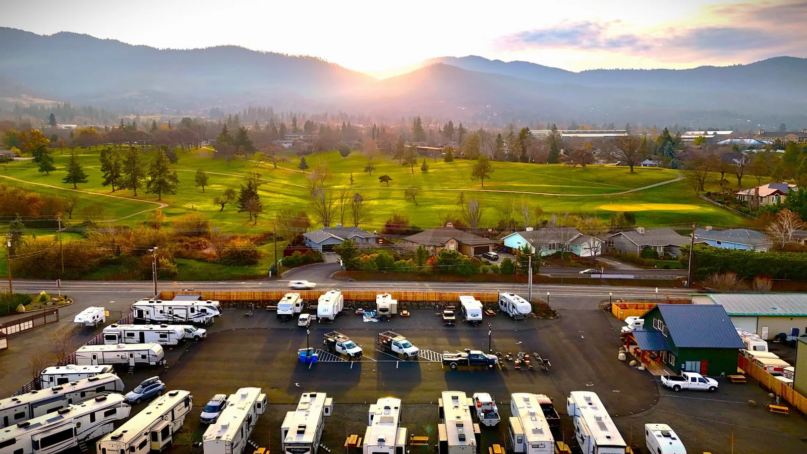 Aerial view of Ashland RV Park, its RV sites and lodge beneath the Southern Oregon hills at sunrise
