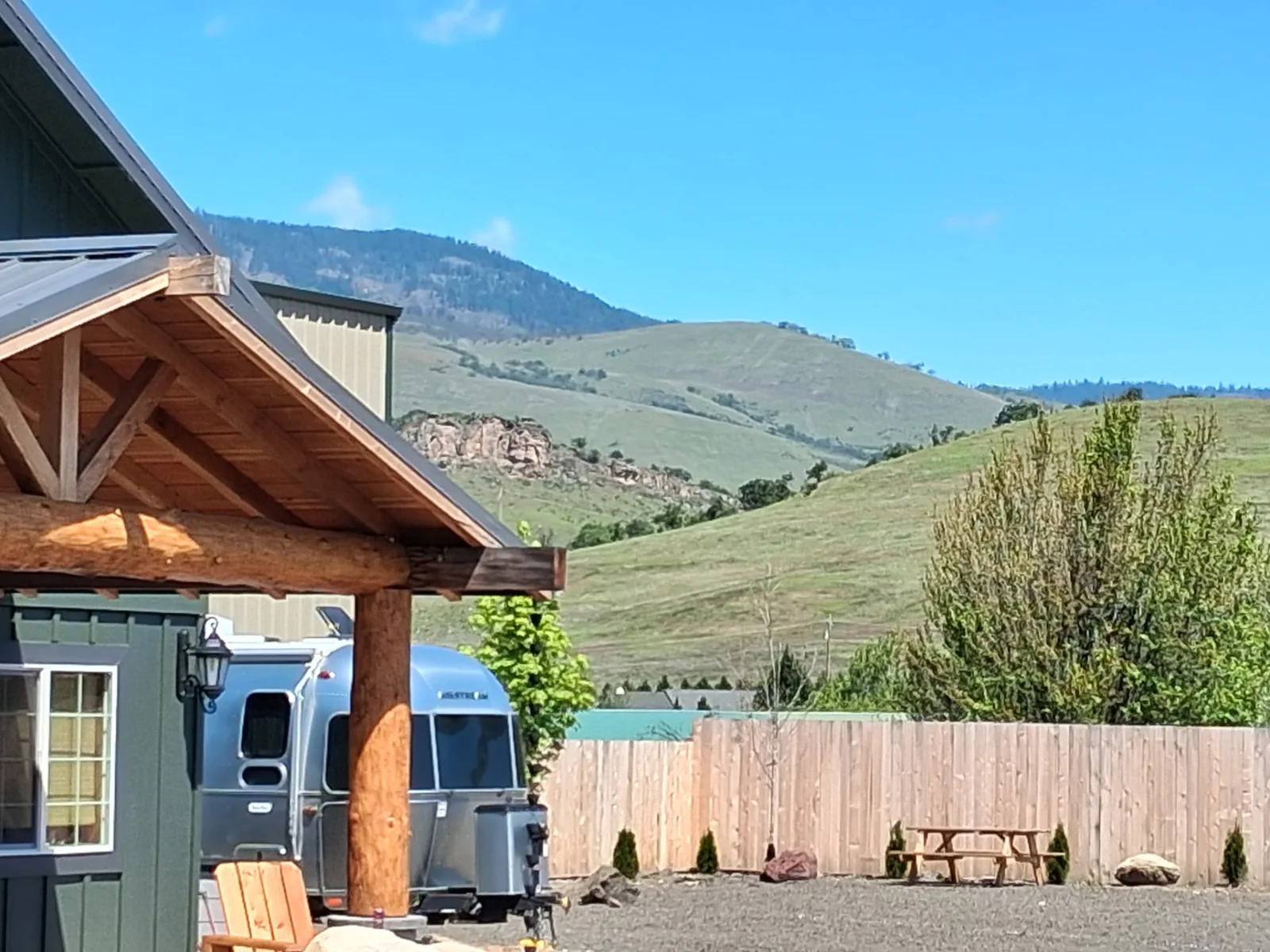 Airstream trailer parked beside the lodge with hills beyond